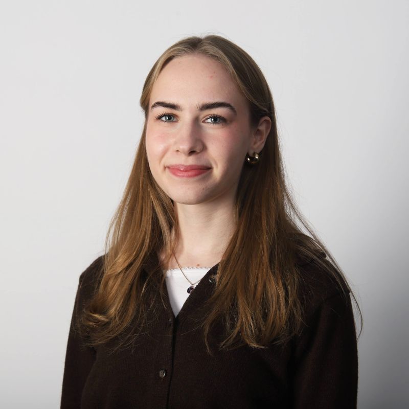 Portrettbilde av Inger Asperud med hvit bakgrunn og brun genser.